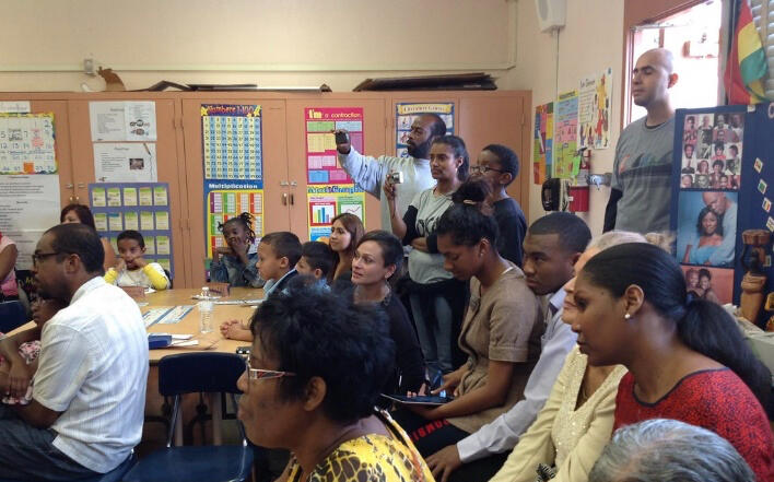A school classroom filled with parents from mixed backgrounds.